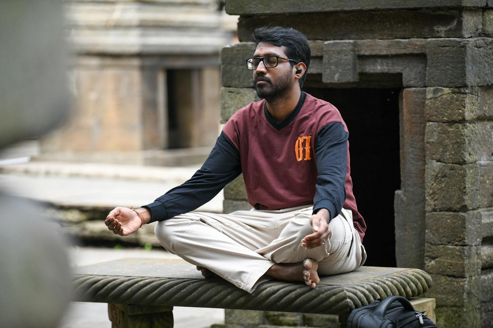 A yatri meditating on a stone bench among the temples.