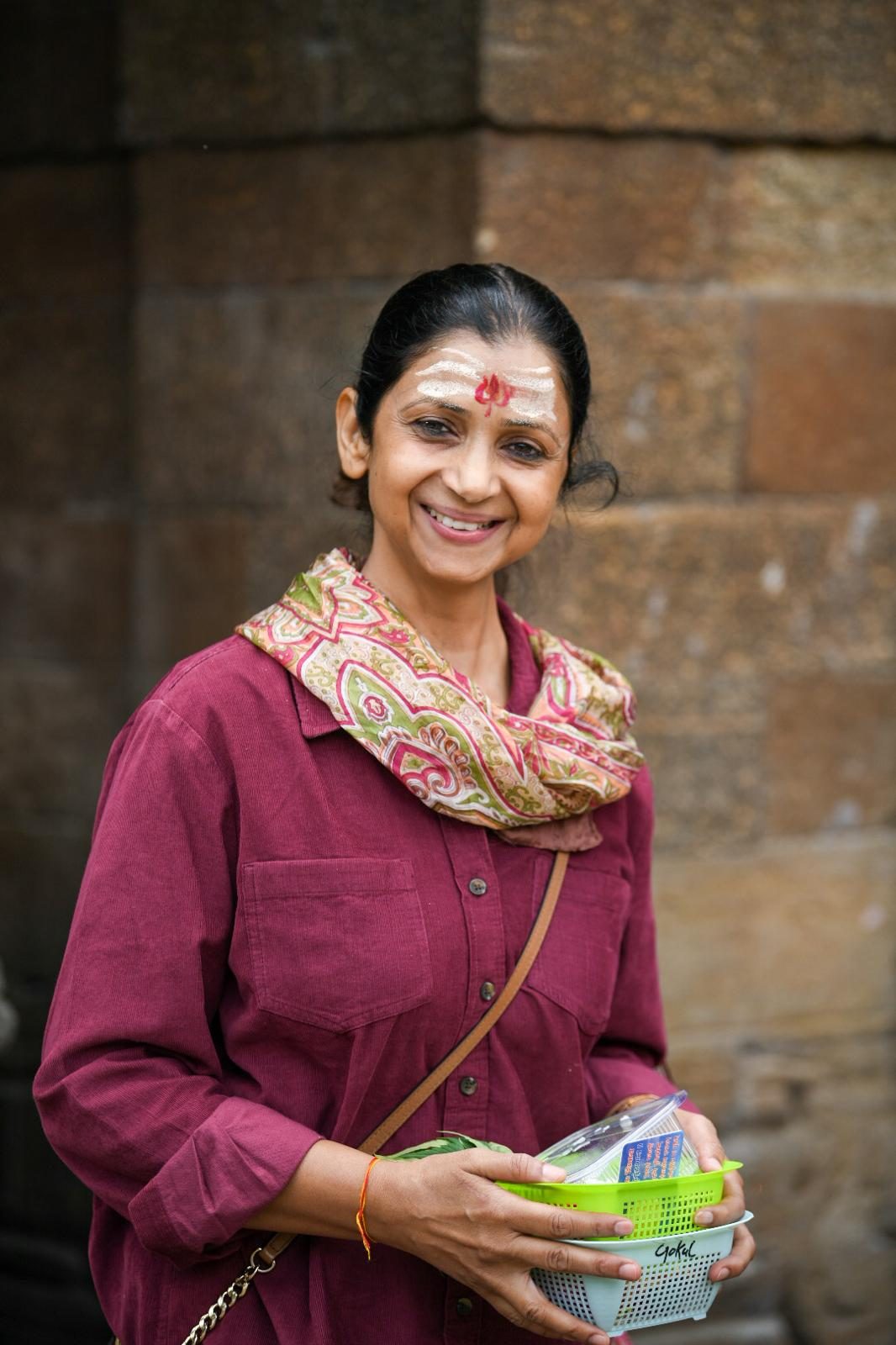A yatri smiling with her temple offerings at Jageshwar Dham.