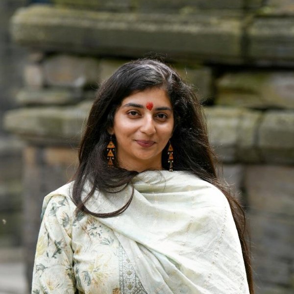 Portrait of Shambhavi Shandilya smiling, in front of ancient stone temples.